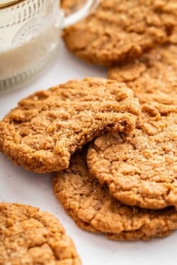 Pile of almond butter cookies with top cookie bitten into.