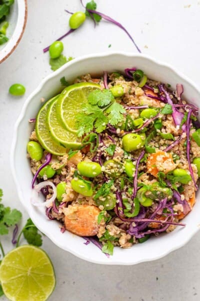 Overhead of an Asian quinoa salad in a white bowl garnished with fresh lime slices.