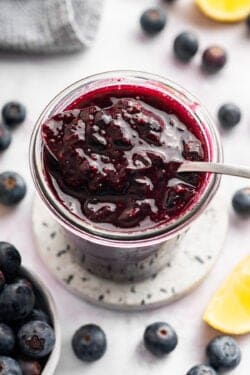 Spoonful of blueberry compote in jar.