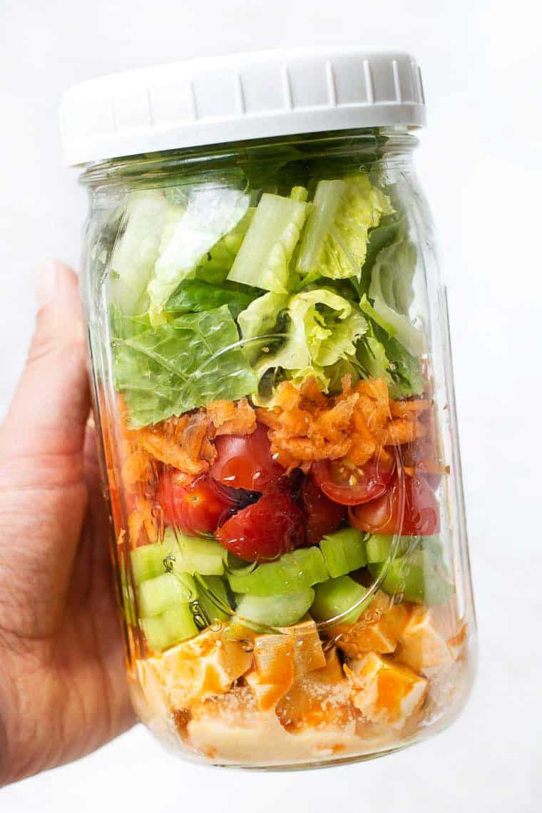 Hand holding meal prep salad in mason jar