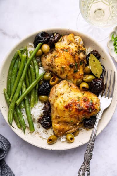 Overhead view of chicken marbella on plate with rice and green beans