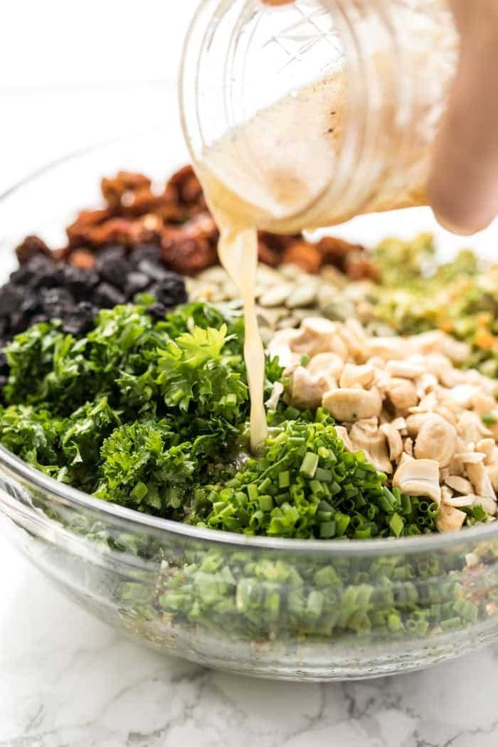 Pouring homemade salad dressing into bowl of salad