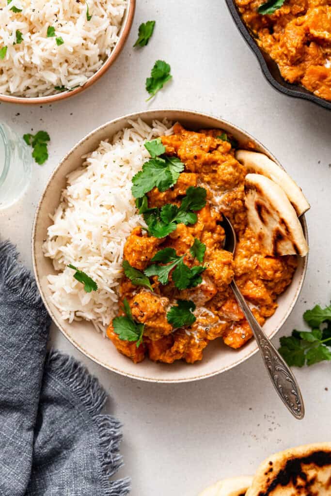 bowl of sweet potato and red lentil curry with rice and naan