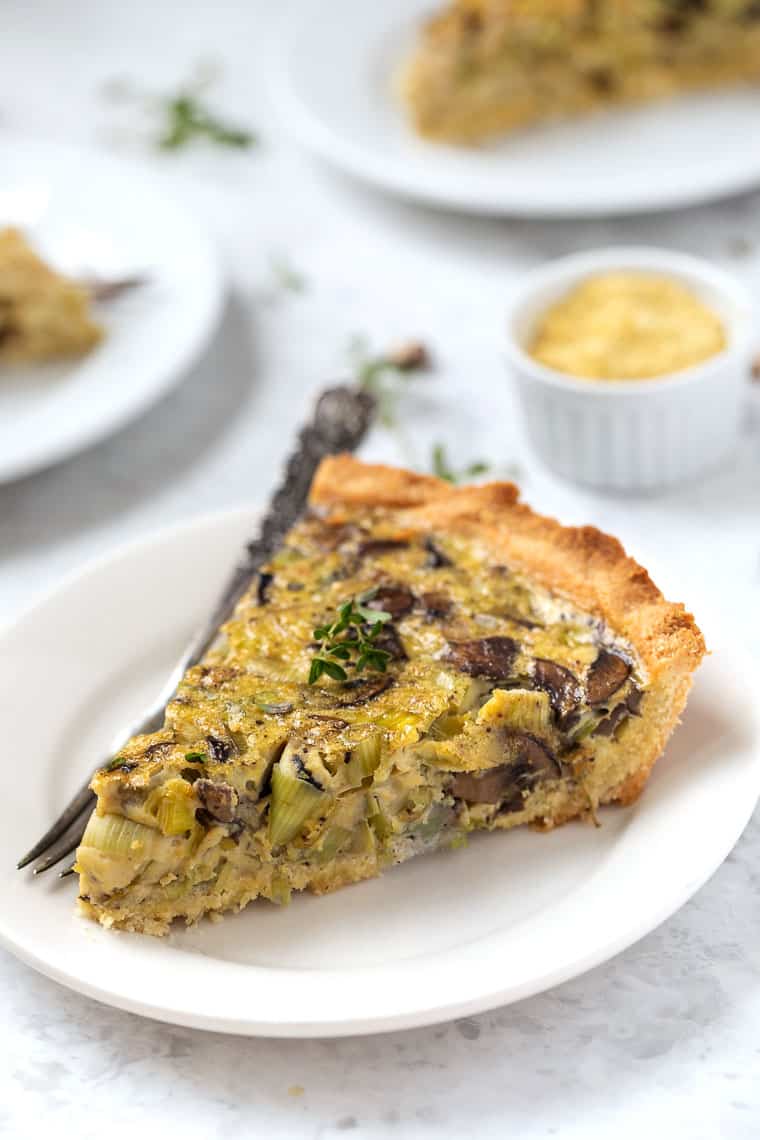 Slice of mushroom quiche on plate with fork