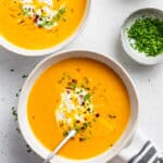 Two bowls of ginger sweet potato soup with chives.