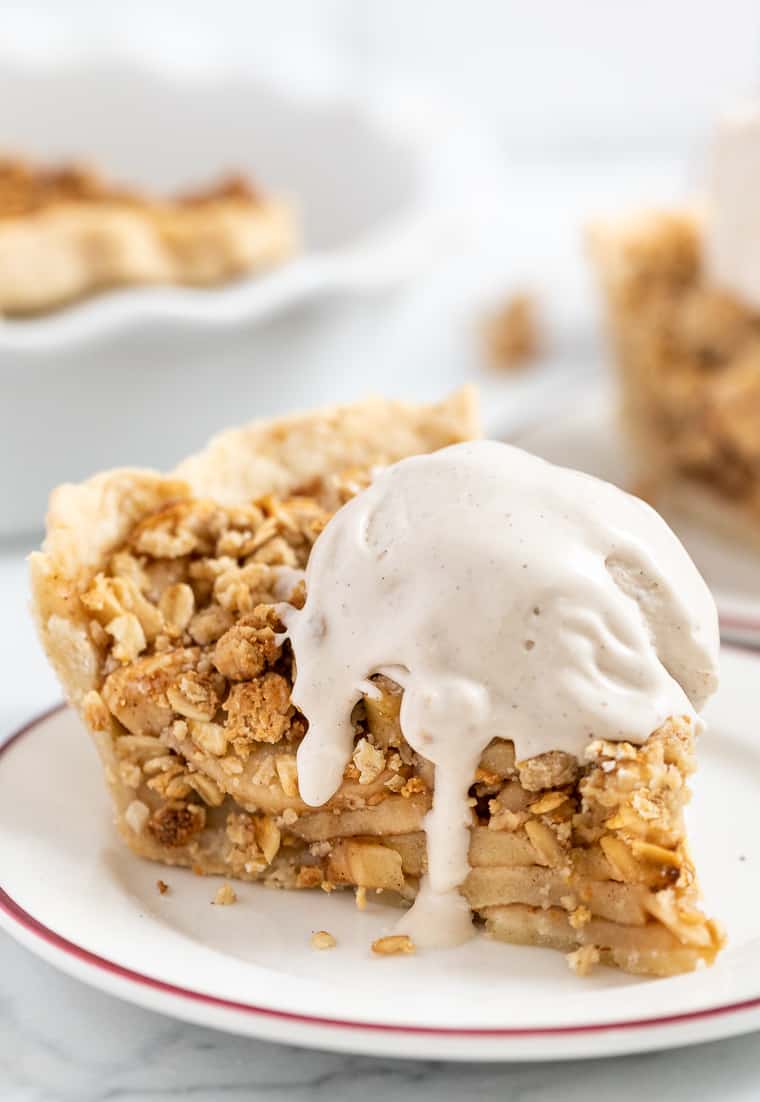 A slice of gluten-free and vegan apple crumb pie topped with ice cream on a plate.