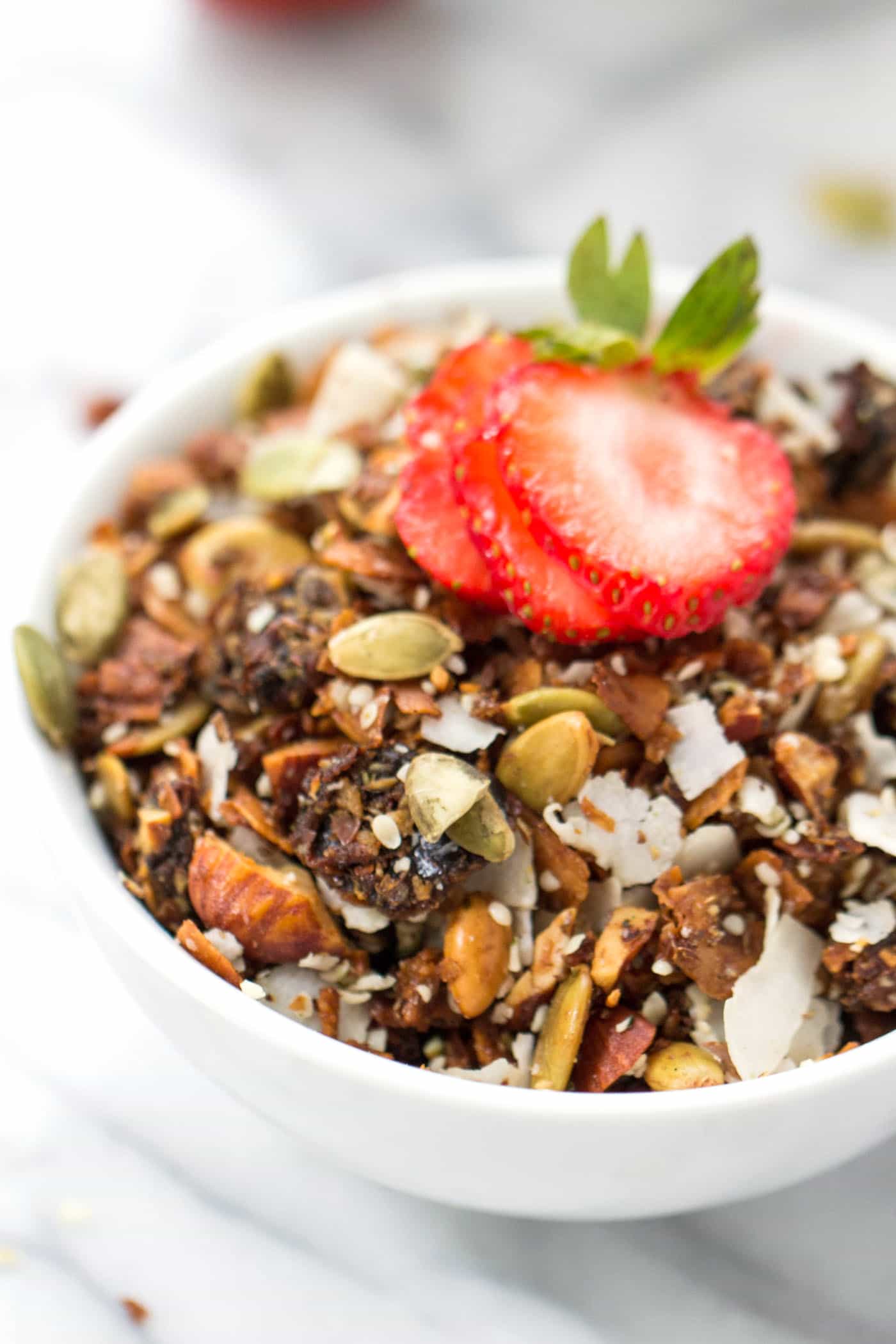 Bowl of grain-free coconut granola with sliced strawberry