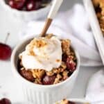 A serving of cherry crumble in a bowl topped with coconut yogurt.