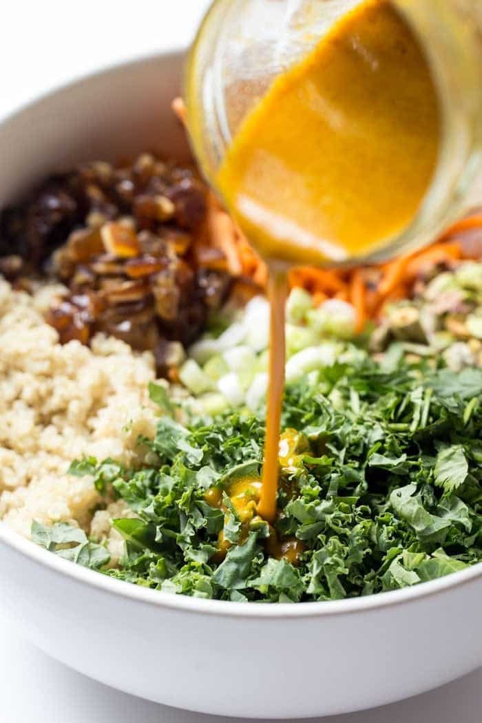 Pouring homemade salad dressing into bowl of salad ingredients
