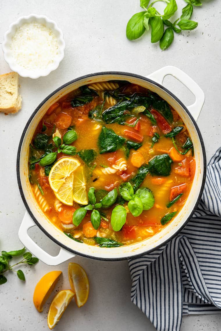 Overhead view of pot of vegetable stew with lemon wedges