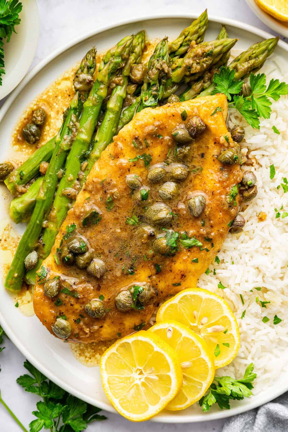 Lemon caper chicken on plate with rice and asparagus