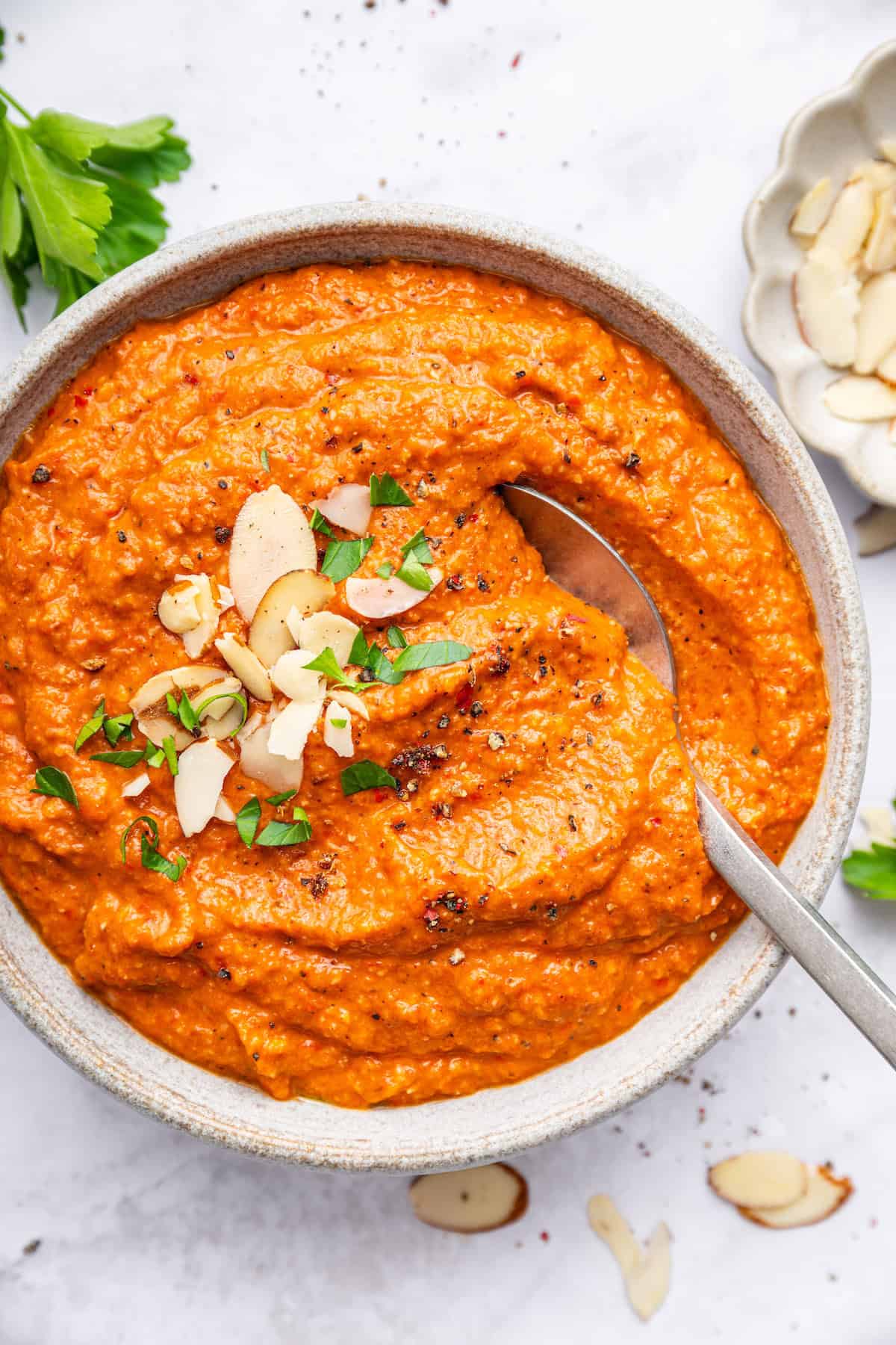 Romesco sauce adds a little pizzazz to so many foods, from grilled vegetables and meats to crusty bread. It’s easy to make and delicious! Overhead view of romesco sauce in bowl with spoon
