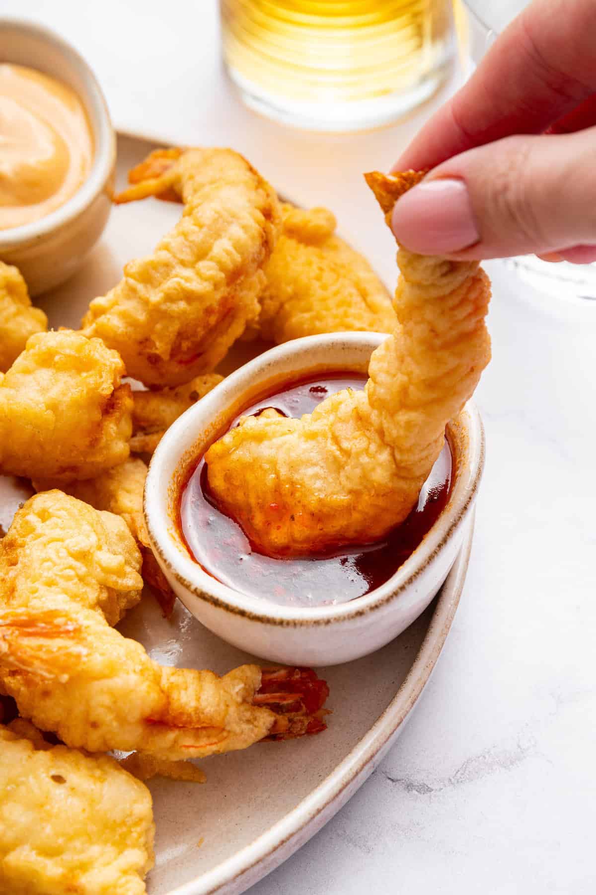Dredge them in cornstarch. Generously sprinkle cornstarch on your shrimp until they’re completely covered. Shake off any excess. Hand dipping shrimp tempura into sauce
