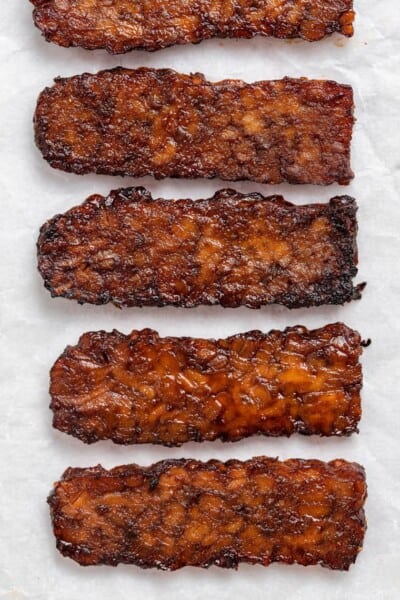 Close up of four strips of cooked tempeh bacon.