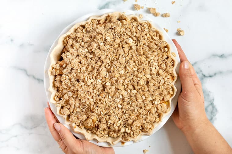 Overhead view of two hands holding an apple crumb pie.