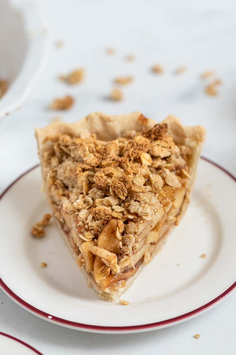Close up of a slice of apple crumb pie on a plate.