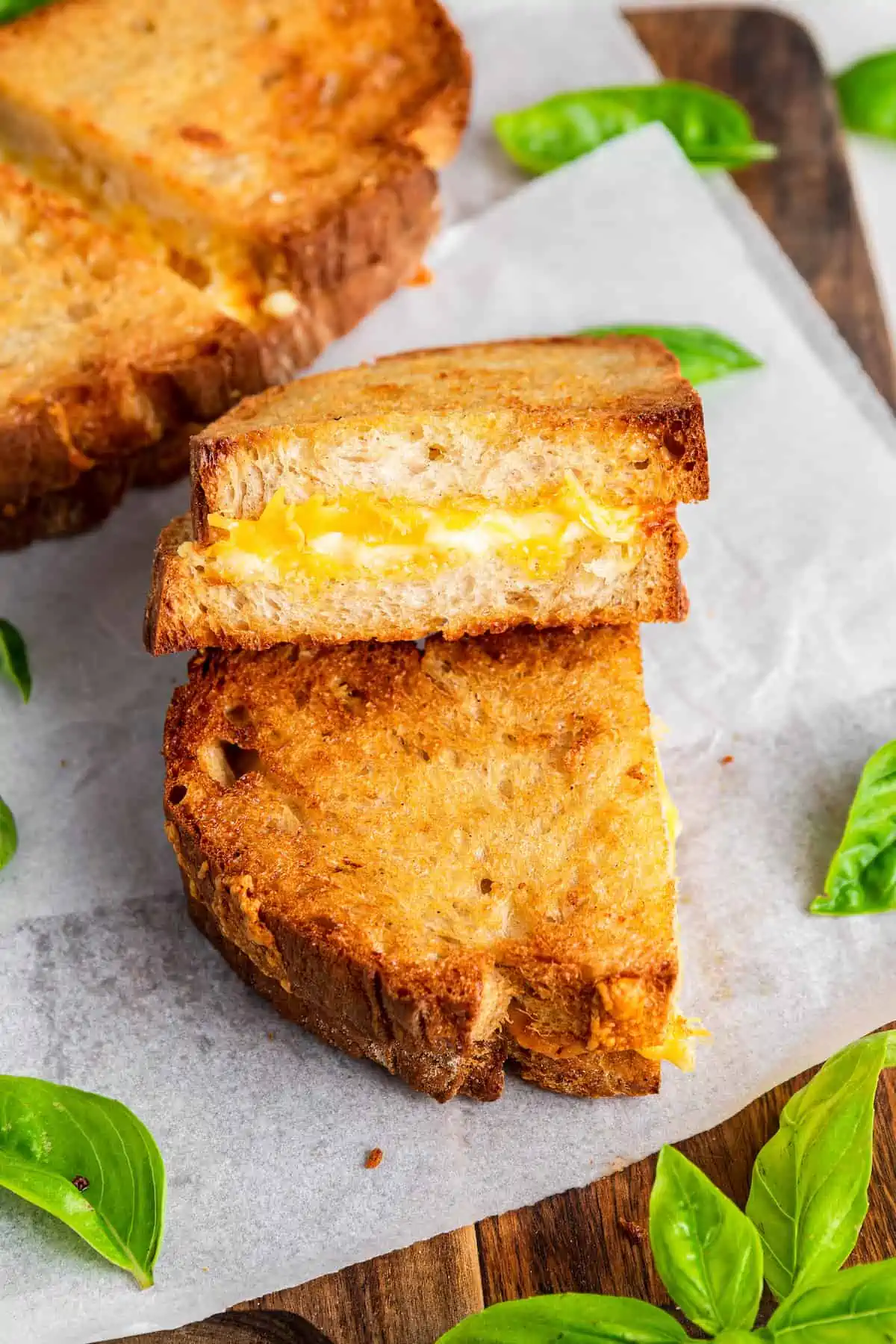 This air fryer grilled cheese recipe makes the BEST sandwich in minutes! Crispy outside, melty inside, and you can make it vegan! Two halves of a vegan grilled cheese sandwich stacked on top of one another, showing the melty cheese inside.