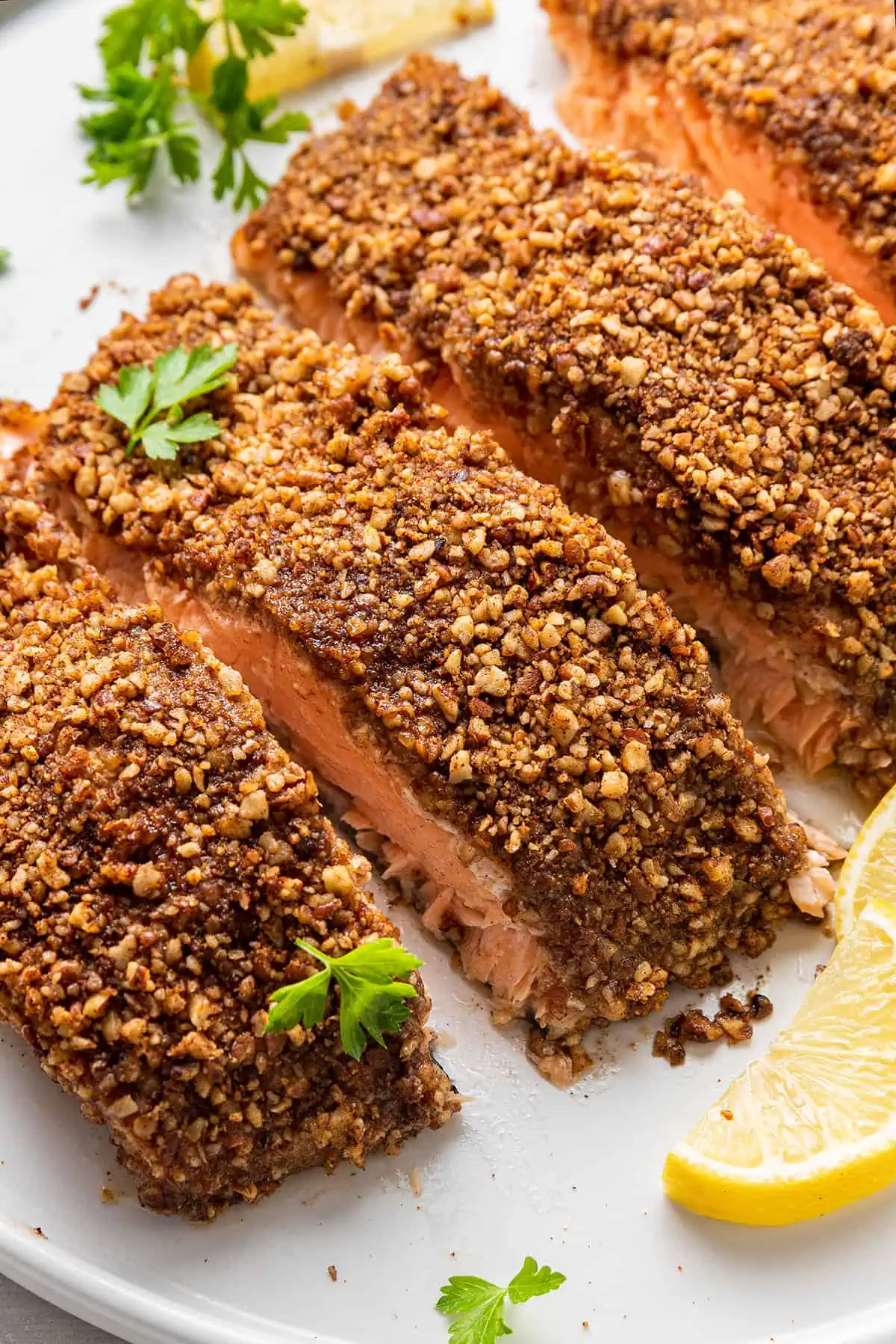 Four cooked salmon fillets crusted in pecans.