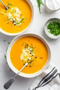 Two bowls of ginger sweet potato soup with chives.