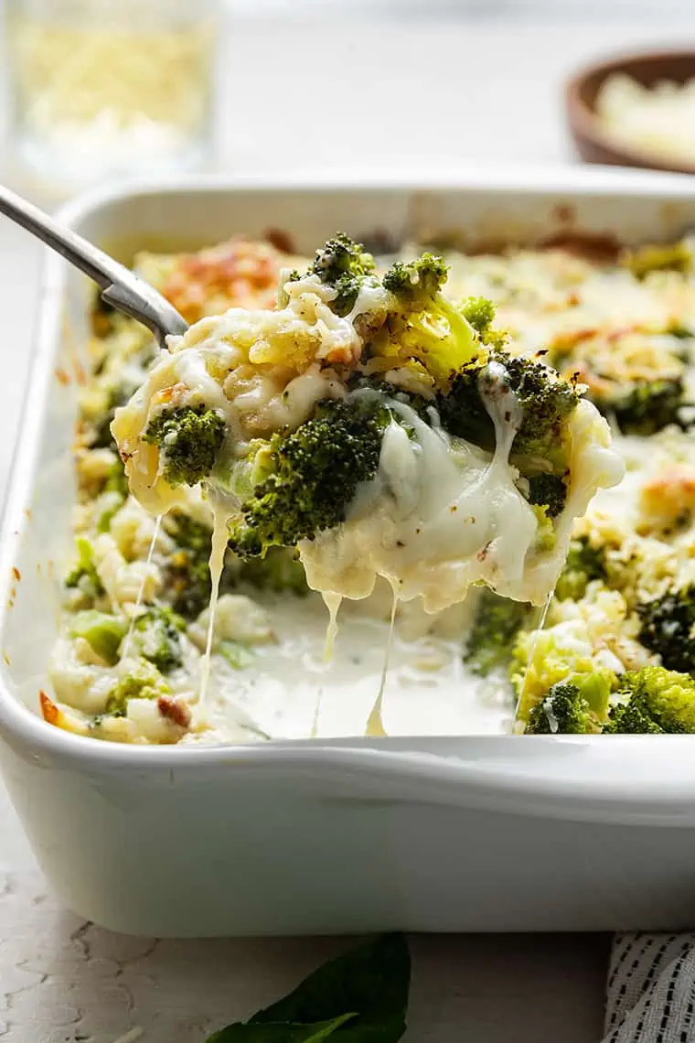 Broccoli casserole being spooned out of a baking dish.