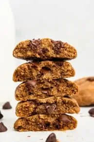 Stack of vegan chocolate chip cookies cut in half to show thick, chewy texture.