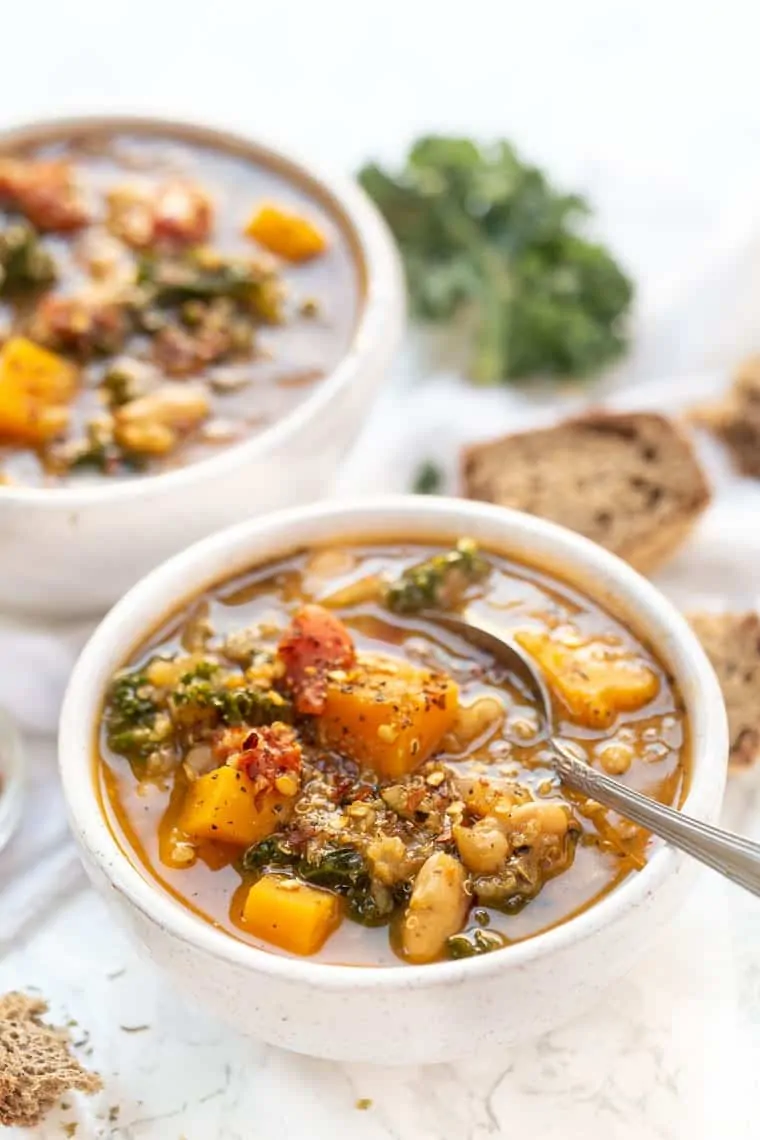 A bowl of Tuscan kale white bean soup with a second bowl in the background.