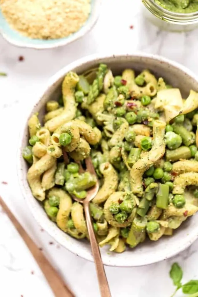 This one-pot asparagus pasta recipe is the best kind of weeknight dinner—easy and delicious! Pesto adds bright, fresh flavor. Overhead view of asparagus pasta with peas and artichokes in bowl